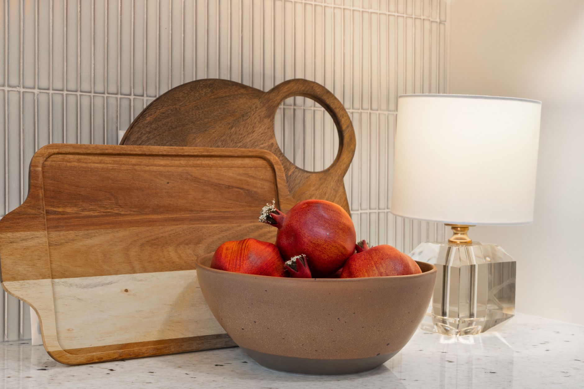 Wooden serving boards and a bowl of fruit on a kitchen counter