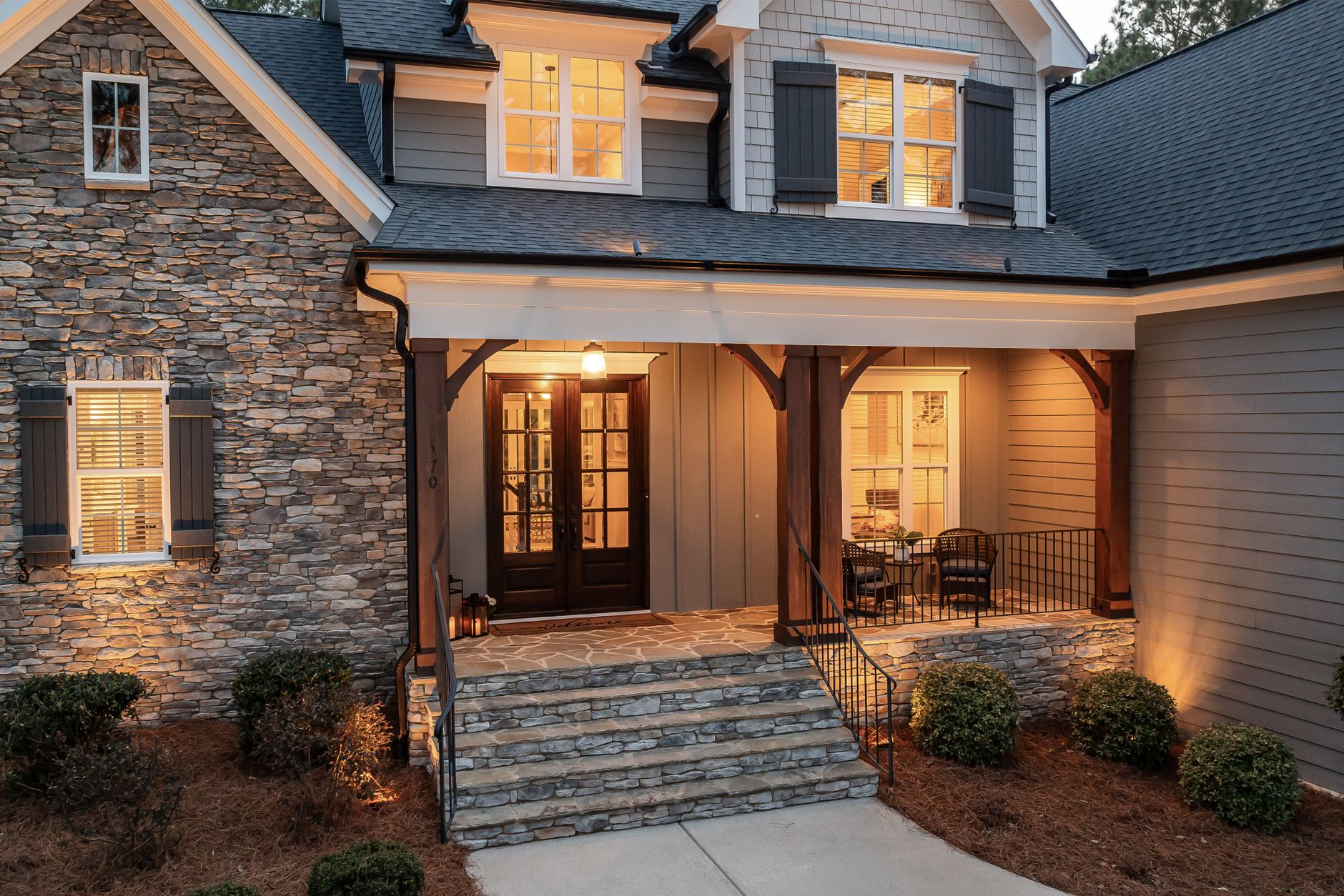 Covered stone entry of a home lit warmly in the evening