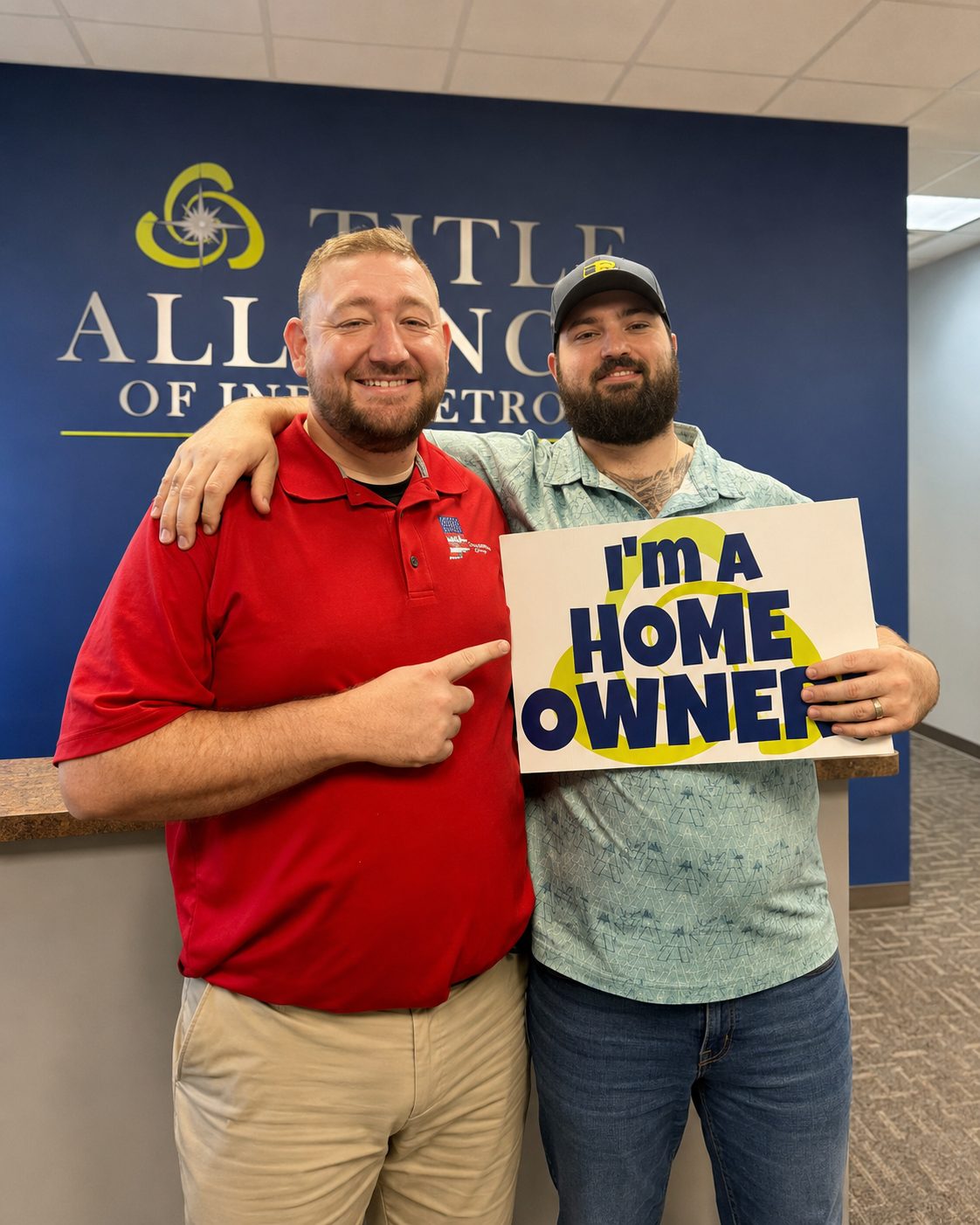 Trae Wilson with a new homeowner holding an I'm a Home Owner sign at a title office
