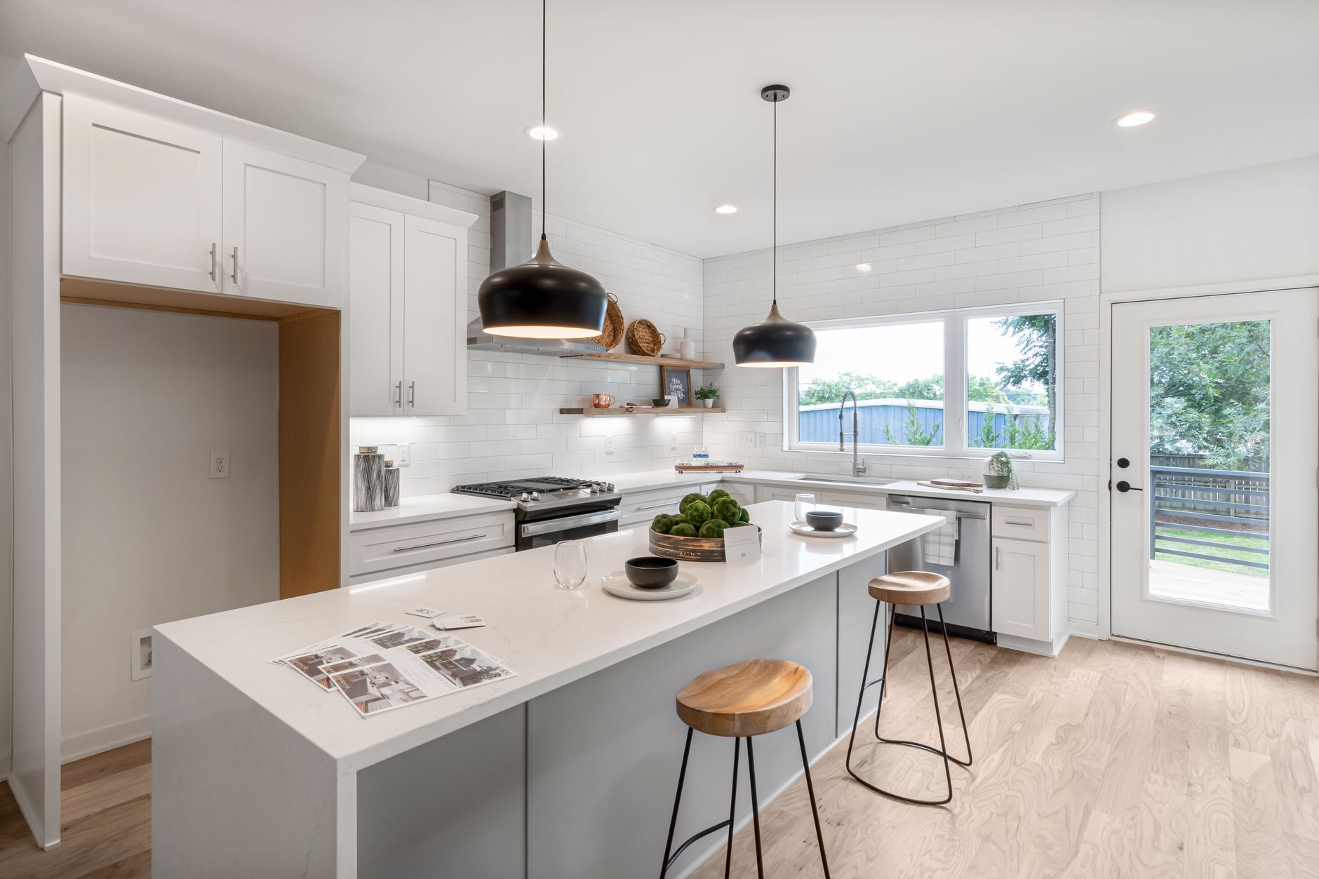 White kitchen with an island, pendant lights and a window